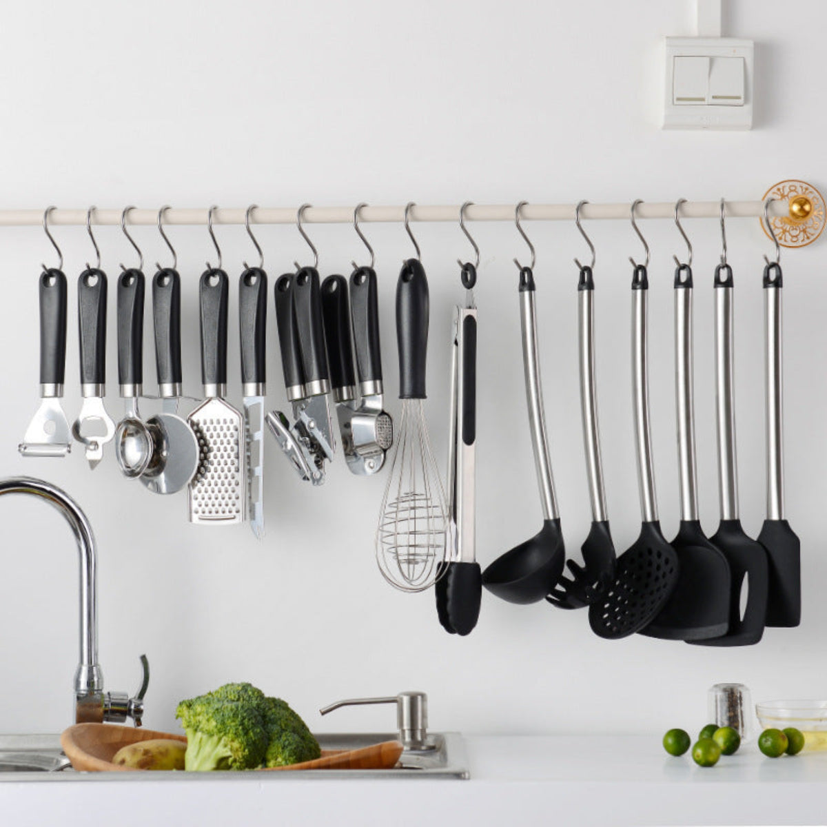 Set of kitchen utensils hanging on a rack above a kitchen counter with vegetables.