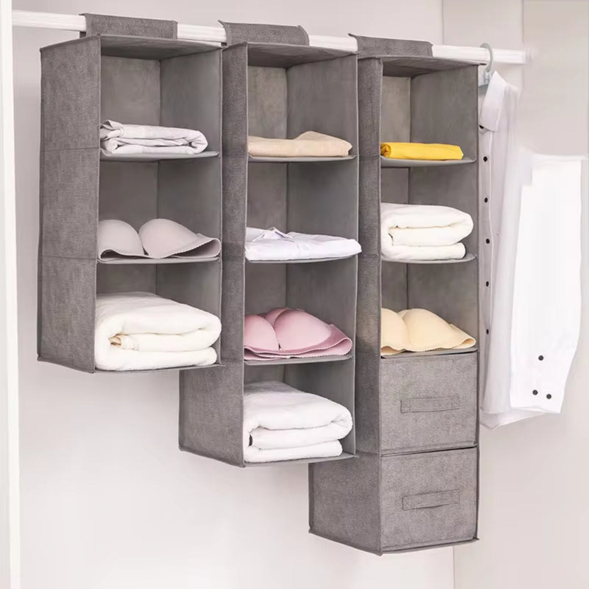 Gray hanging shelf with folded clothes on a white background