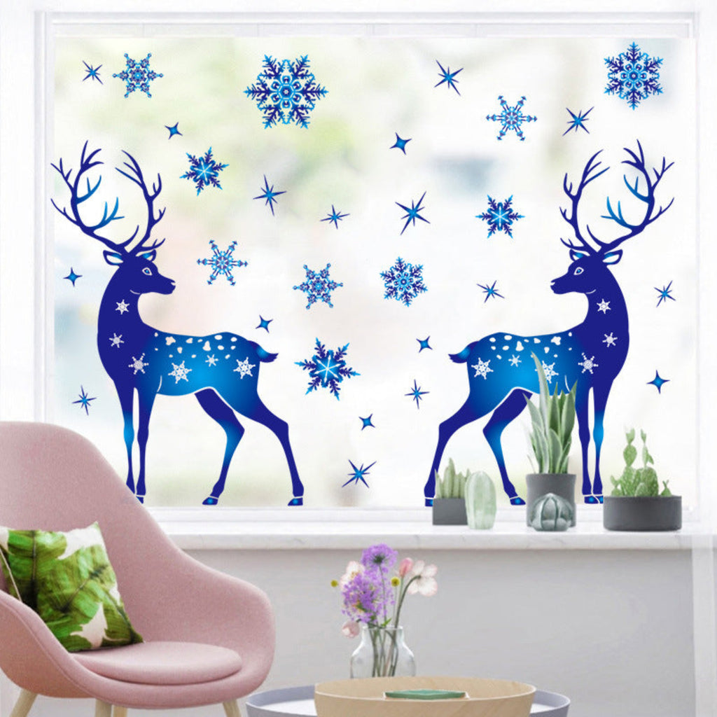 Decorative window stickers of blue deer and snowflakes on a glass pane with a pink chair and plants in the foreground.